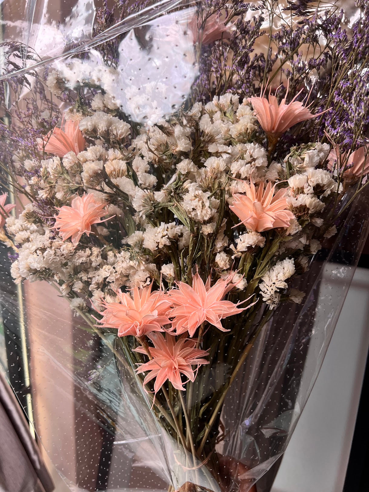 Bouquet of pink and white flowers in a clear vase with water droplets on the glass.