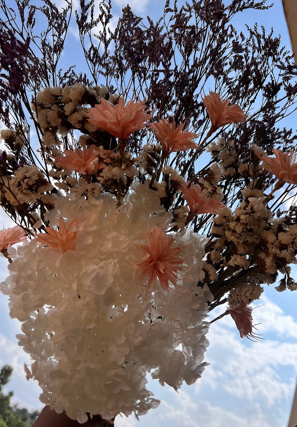 Bouquet of flowers with brilliant colours and soft colours existing in nature held against a blue sky with clouds