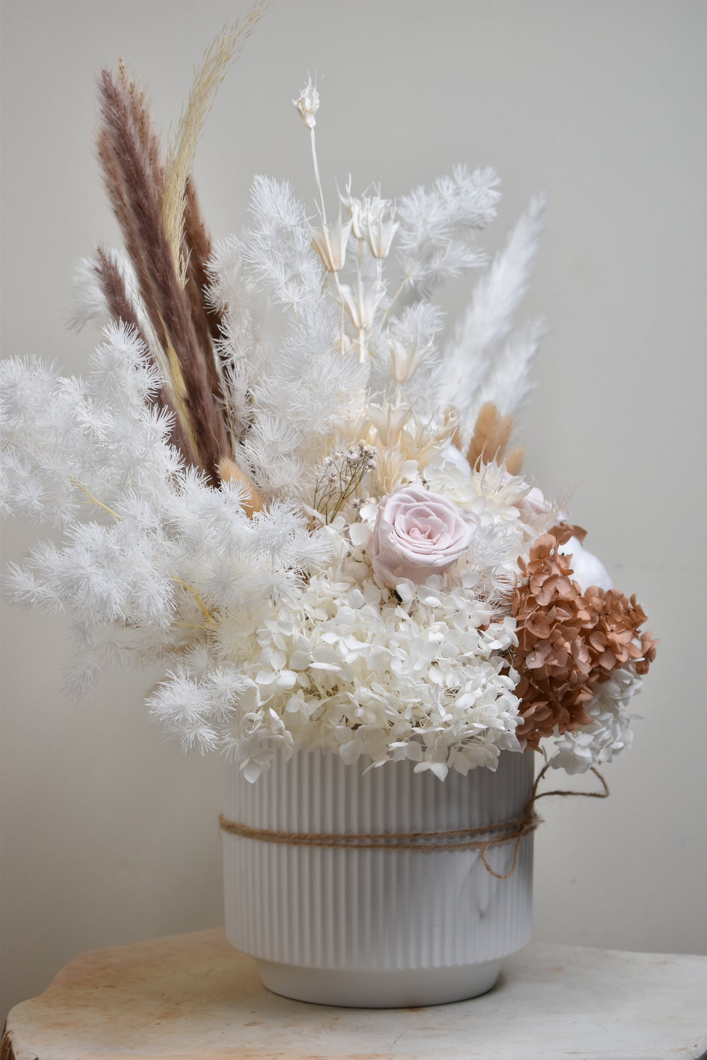 The Issadora muted preserved flower arrangement from kenyan lady fleur on soapstone decor piece in hallway.