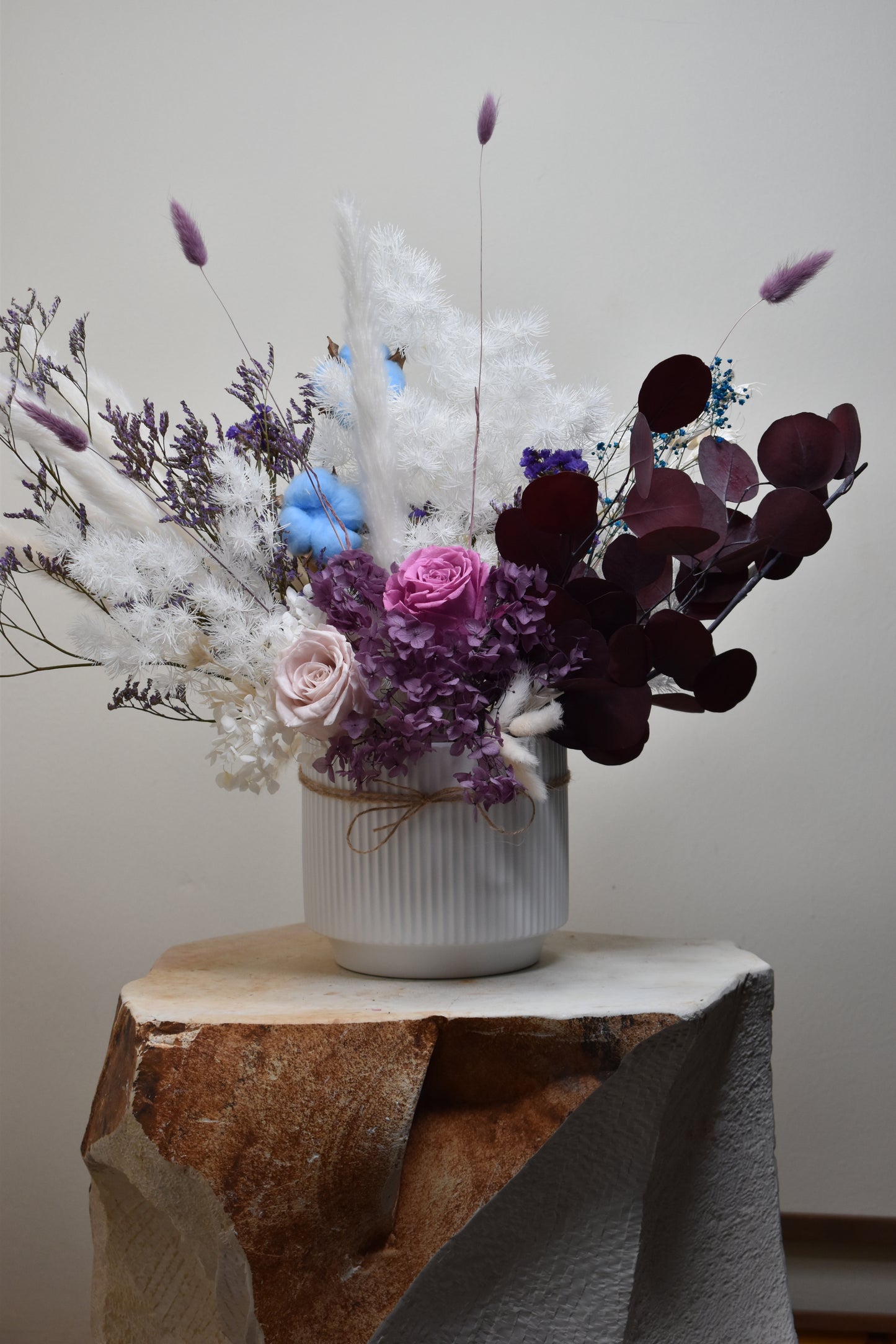 The Christine dried flowers arrangement on a limestone decor piece in the hallway.