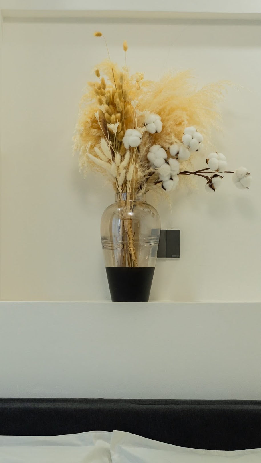 Arrangement with beige pamas grass and other preserved flowers from Kenyan Lady Fleur dried flowers store on a headboard.