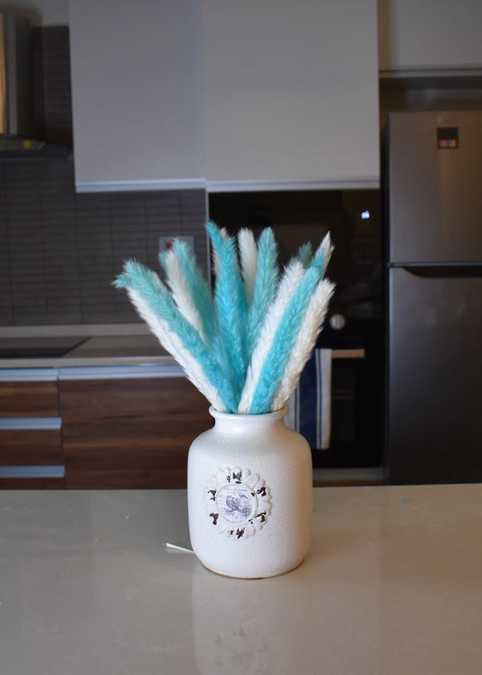 Decorative vase with turquoise blue and white small pampas grass on a kitchen counter.