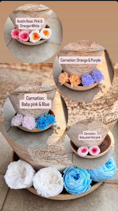 A collage showing several preserved flower bouquets in round wooden bowls, with circular callout windows labeled with names such as Austin Rose Pink & Orange/White, Carnation Orange & Purple, Carnation Baby pink & Blue, and Carnation Baby pink/white. The flowers are arranged on a stone surface against a neutral stone background.