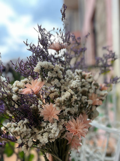 Bouquet of dried flowers with purple, pink and white blooms against a blurred background