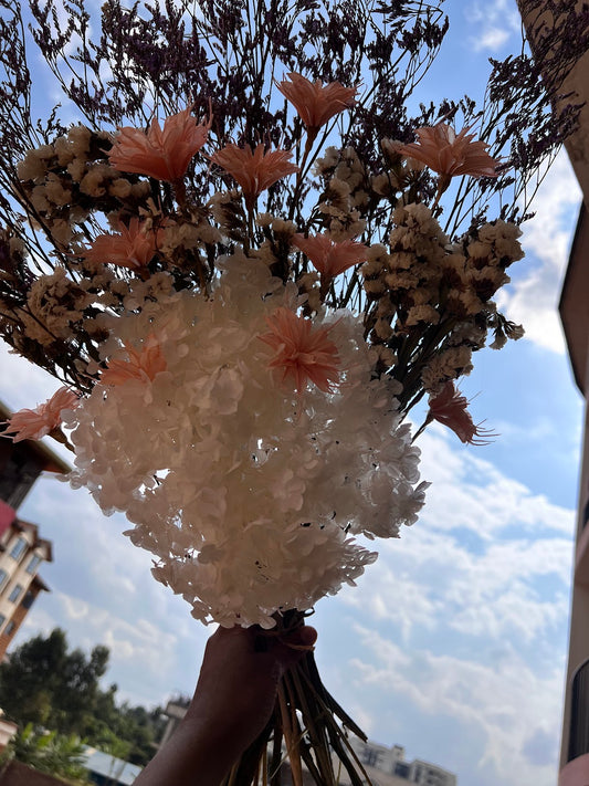 Bouquet of flowers with brilliant colours and soft colours existing in nature held against a blue sky with clouds.