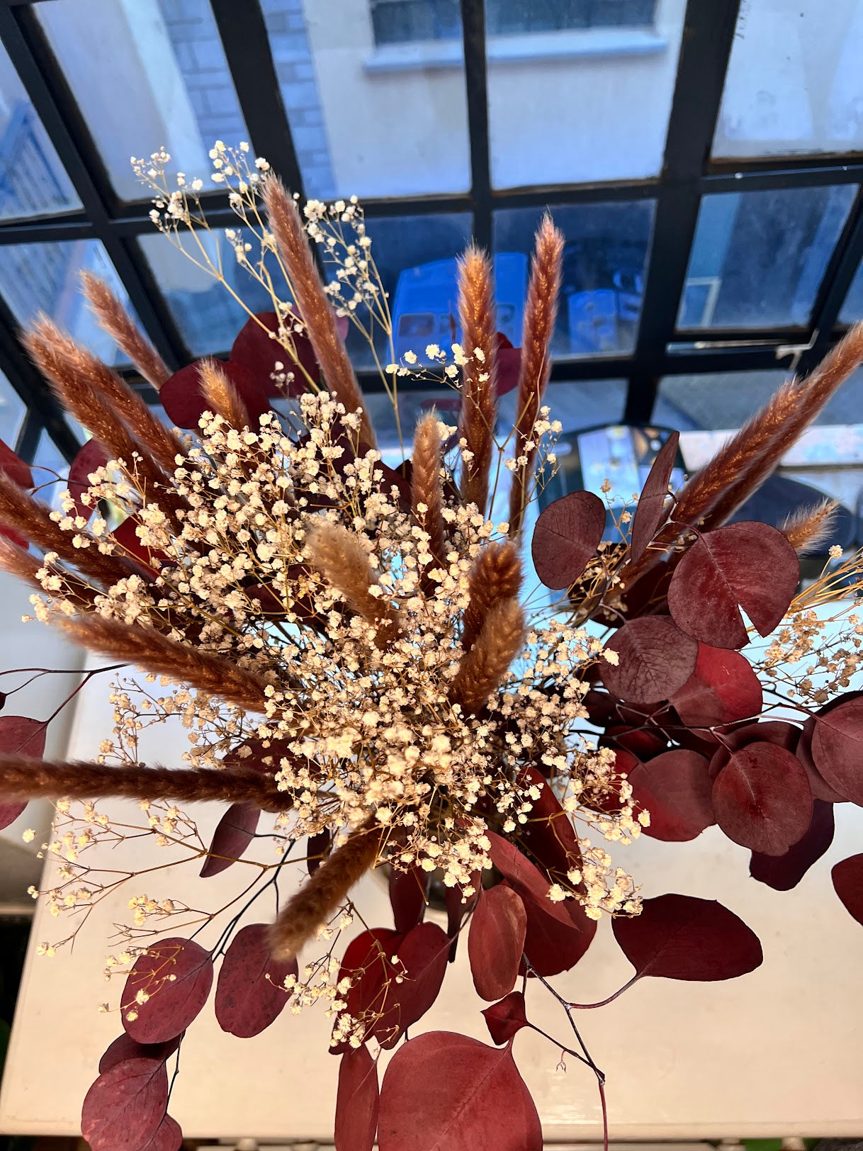 Bouquet of dried flowers with brown and red leaves and small white babys breath flowers and small pampas grass.