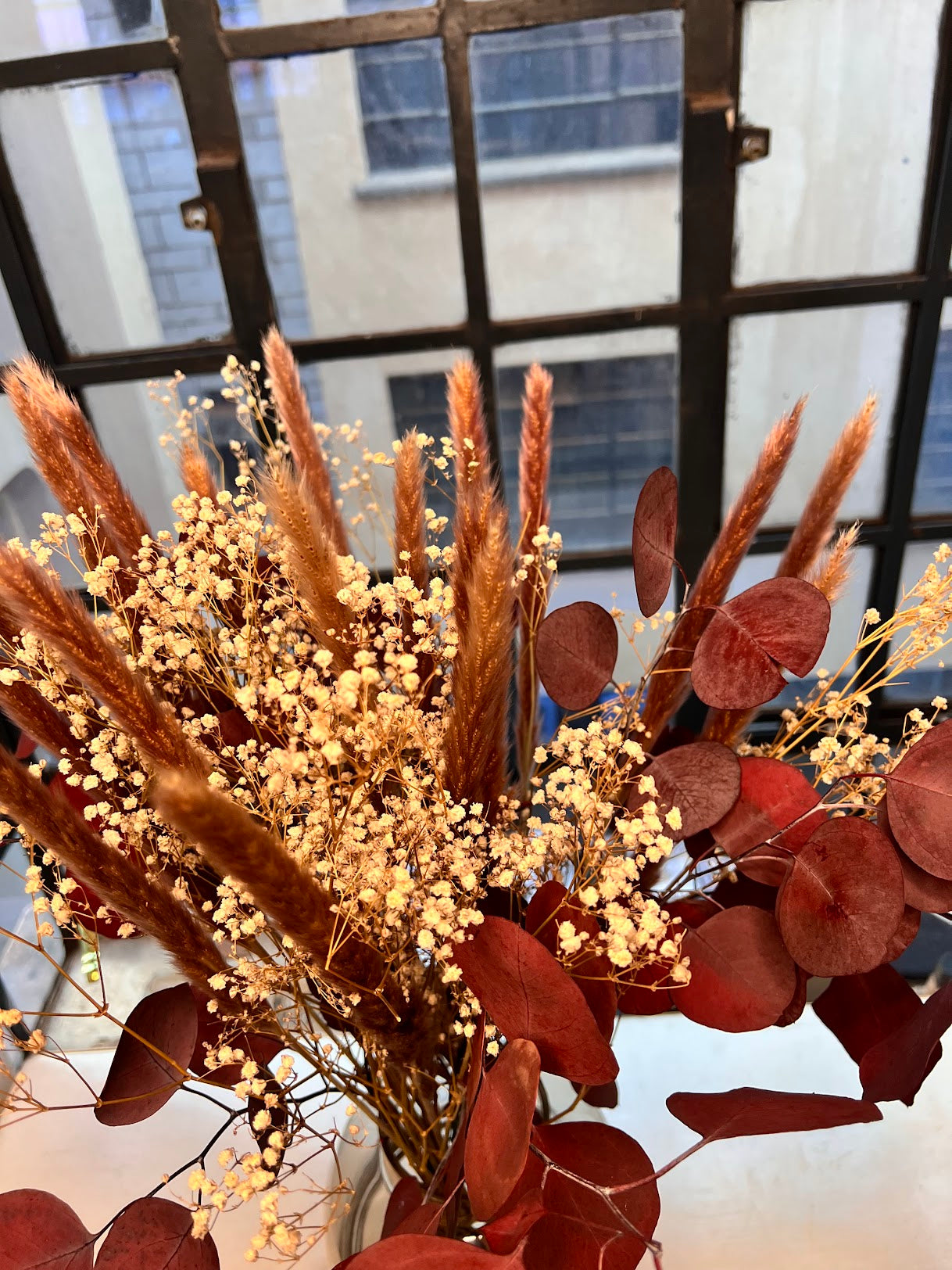 Bouquet of dried flowers red eucalyptus with a blurred window background