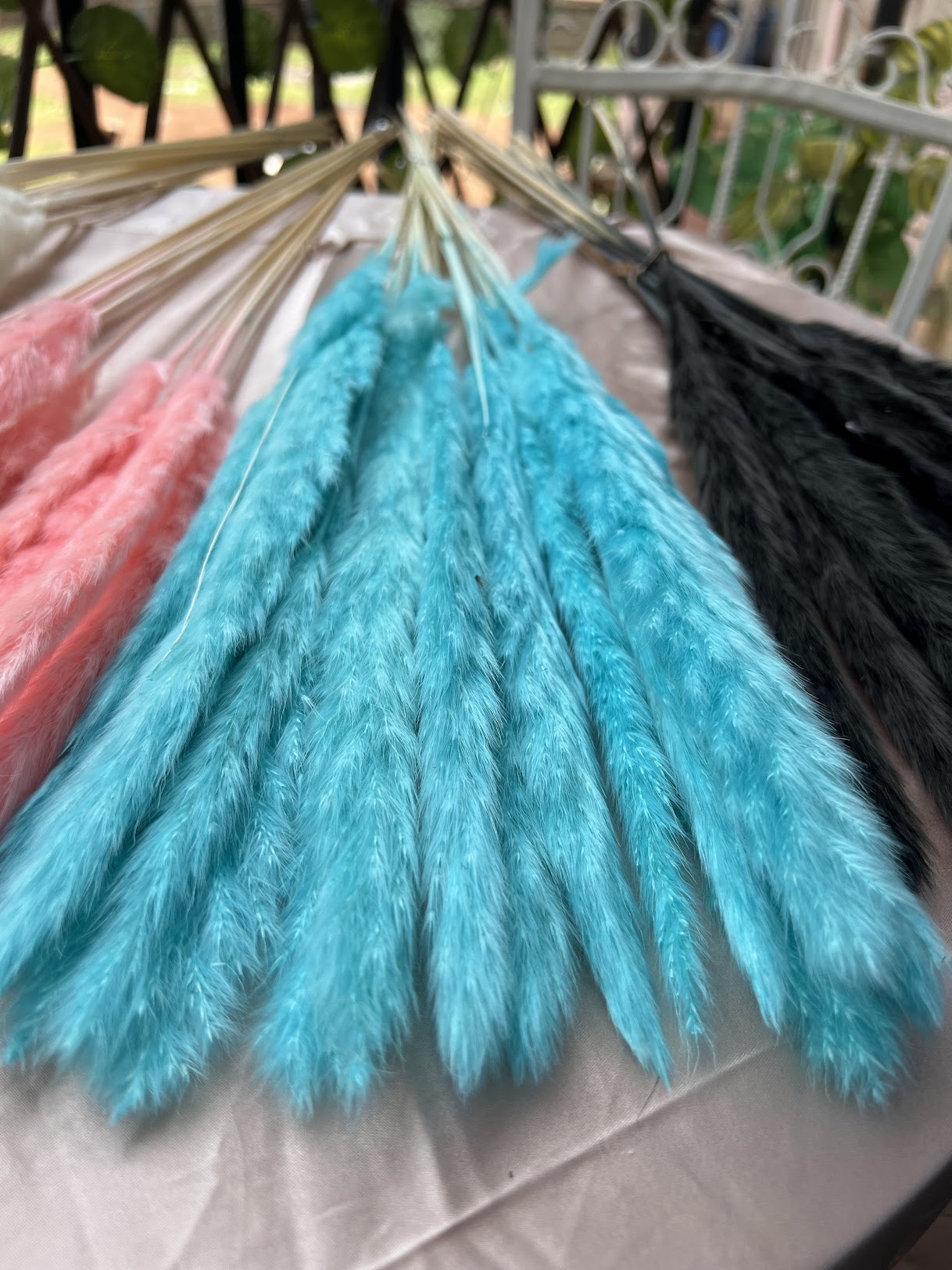 Bunch of blue dried grasses with pink and black grasses in the background.