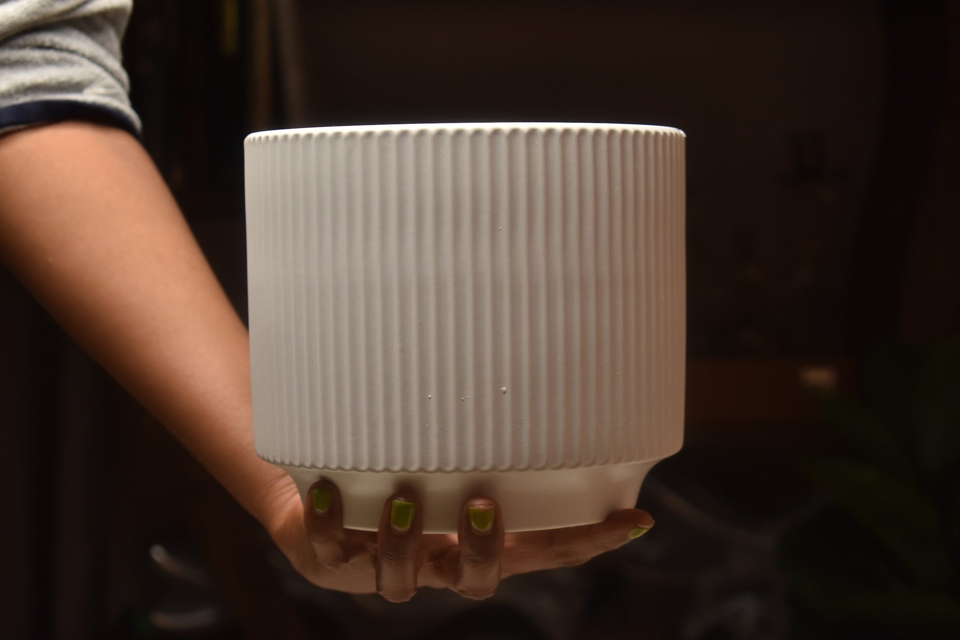 Person holding a white ribbed vase from kenyan lady fleur. 