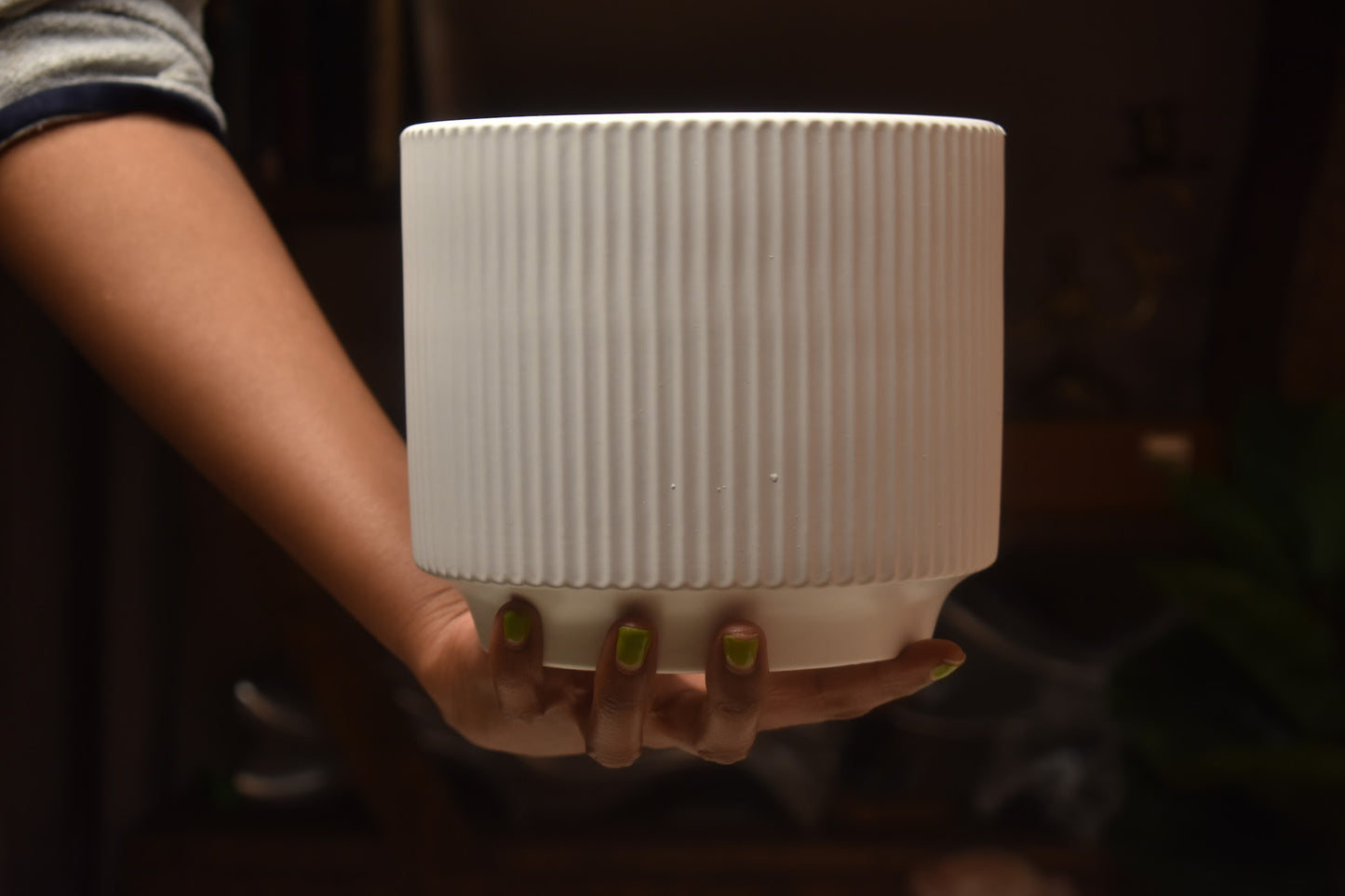 Person holding a white ribbed vase from kenyan lady fleur. 