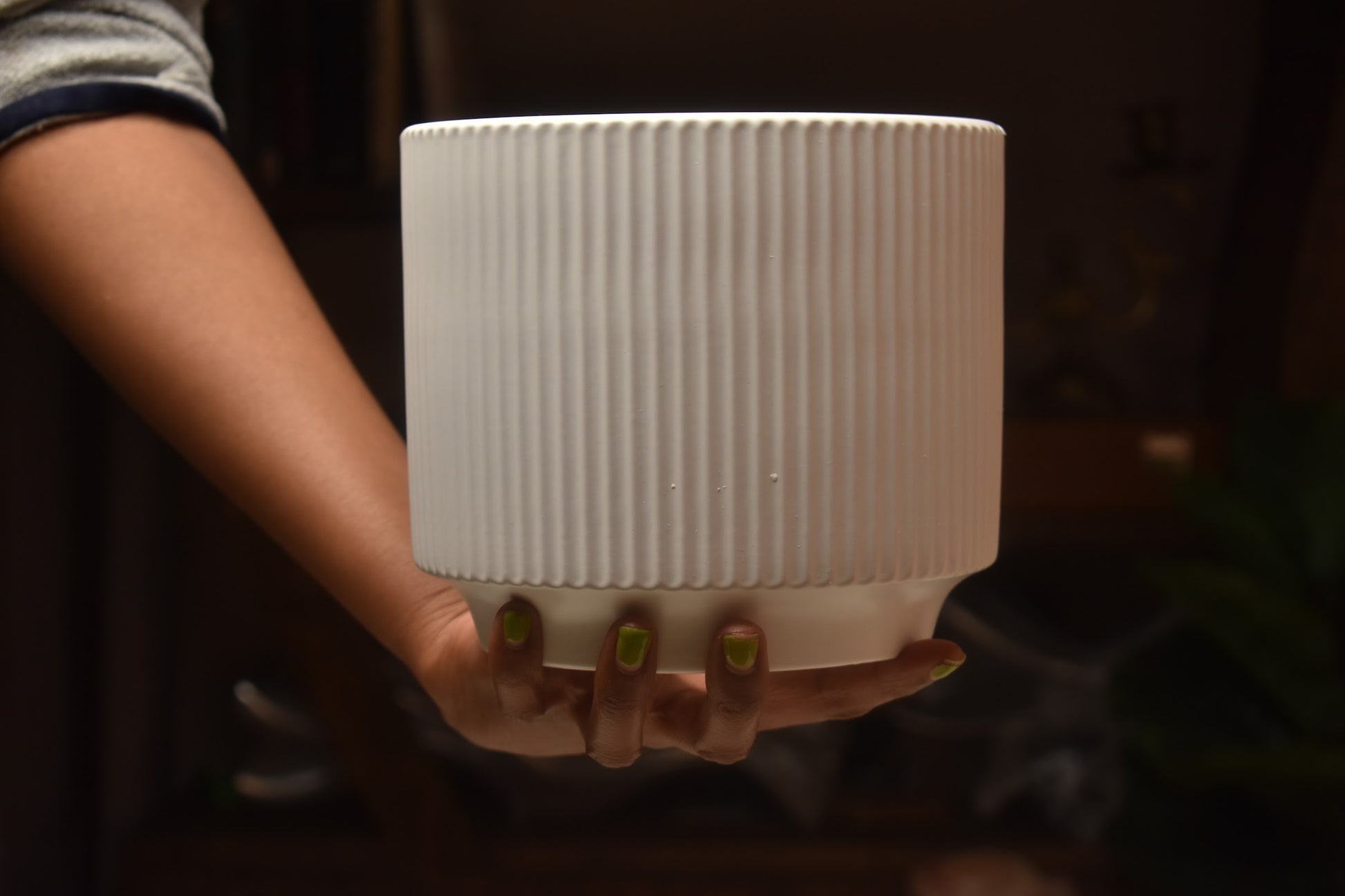 Person holding a white ribbed vase from kenyan lady fleur. 