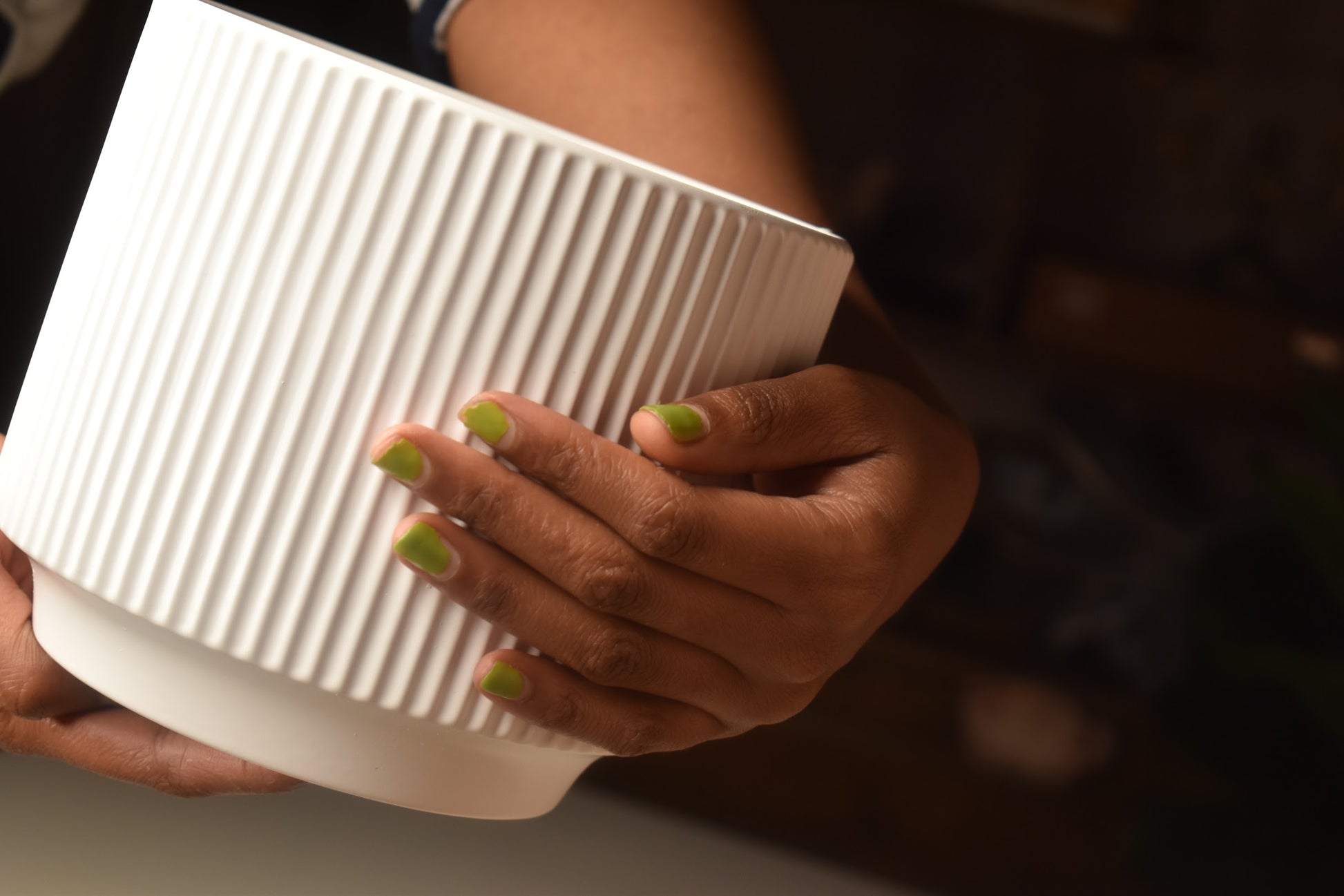 Person holding a white ribbed vase from kenyan lady fleur. 