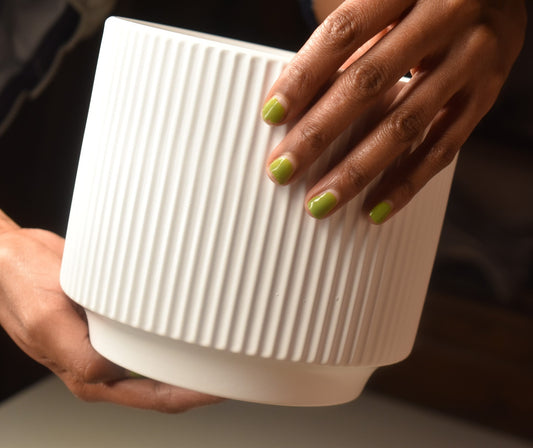 Person holding a textured white ceramic pot from kenyan lady fleur.