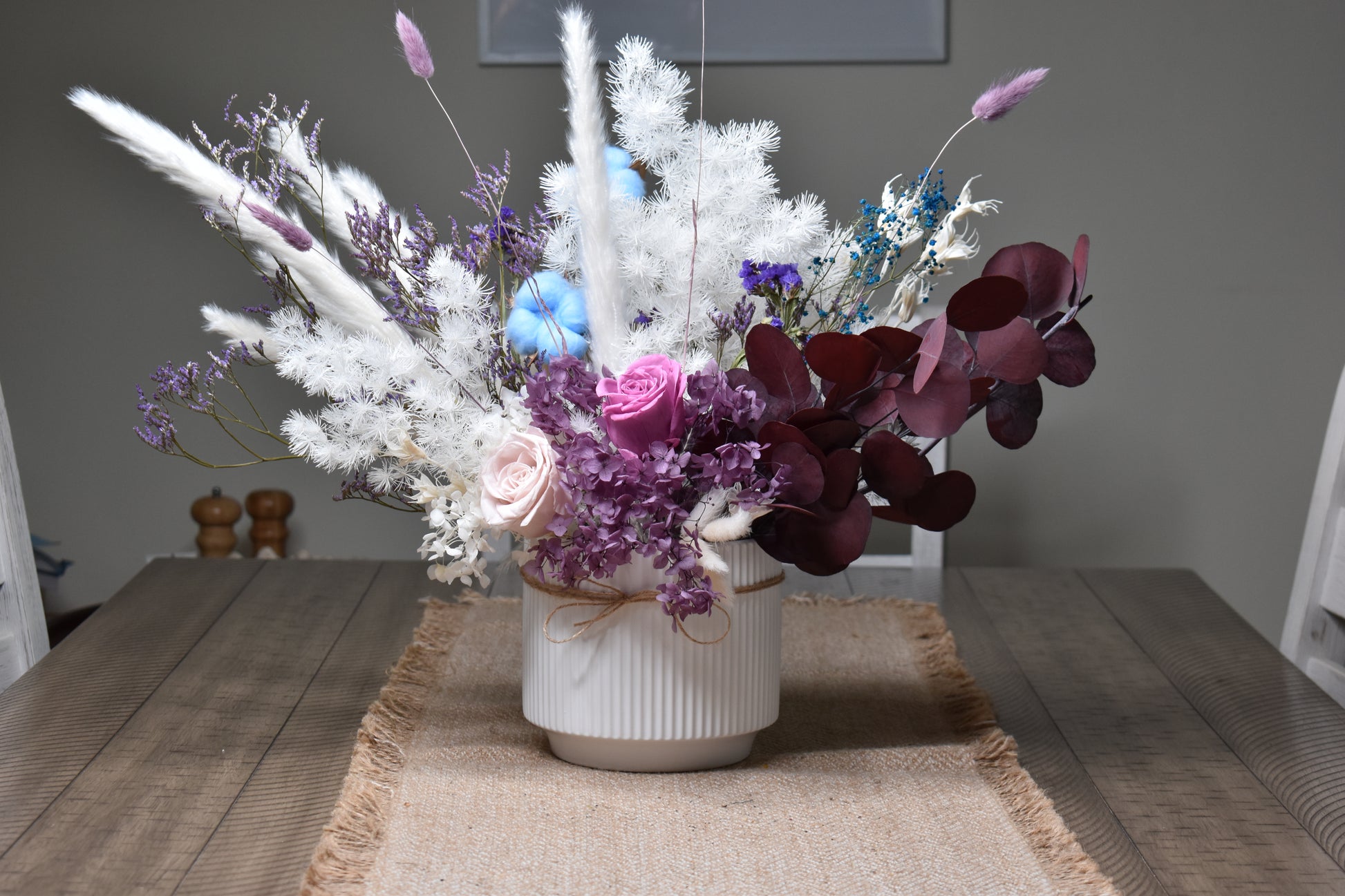 The Christine Dried flowers arrangement set on a 6-seater dining table in a 16.5 cm diameter and 14.5 cm height white vase.